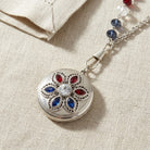 Silver tone Patriotic Red White and Blue Crystal Locket Necklaces on a beige fabric background