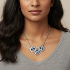 Woman wearing a silver necklace with blue stones on a neutral background