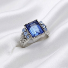 Sapphire Blue glass crystal ring placed on white satin fabric. 