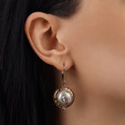 A close-up of a model's ear wearing a Light Rose Pink Crystal & Faux Pearl Pink Flower Decal Drop Earrings
