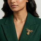 Woman in a green blazer wearing a gold tone bee brooch pin with crystal accents