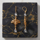 Bee Euro Crystal Dangle Earrings on a gold and black marble stone surface