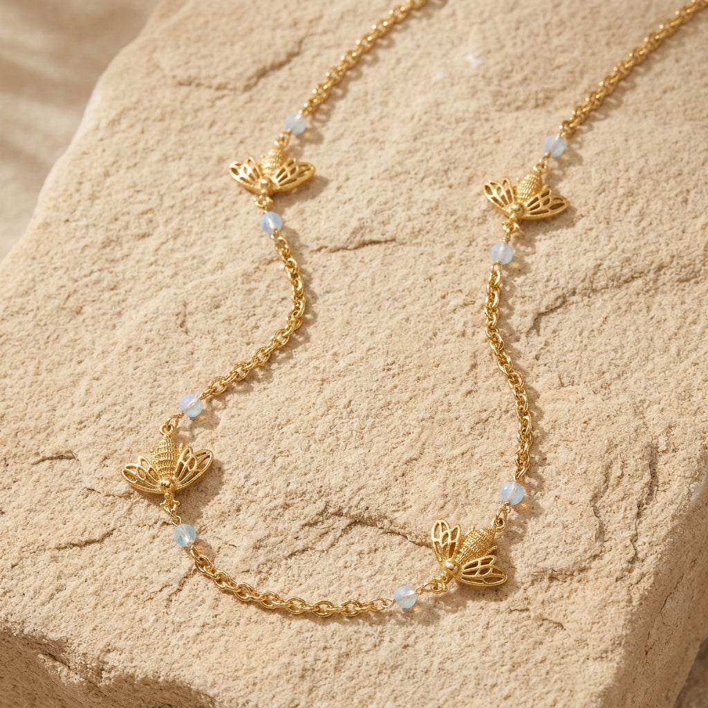 Gold Tone Quadruple Bee AB Crystals Chain Necklace resting on a stone surface