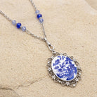 Light Sapphire Crystal Blue Willow Pagoda Oval Swivel Pendant Necklace on beige sandstone surface