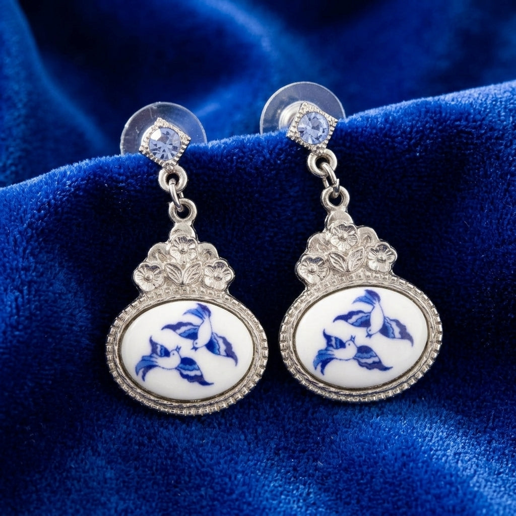 Pair of earrings with two blue birds design on a blue velvet background