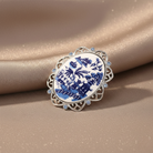 Decorative brooch with blue and white design on a beige fabric background