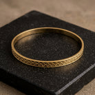 Gold Classic Leaf Bangle Bracelet resting on a slab of dark stone