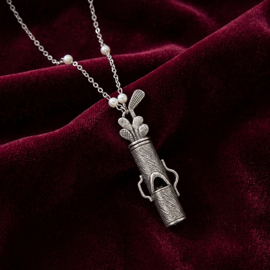 Golf Club Set Whistle Pendant Faux Pearl Necklace resting on dark red fabric