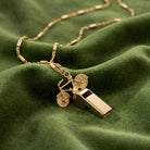Vintage Bike & Functional Whistle Gold Tone Necklace resting on green fabric