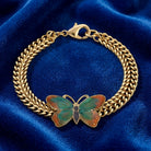 Gold tone bracelet with a multicolored butterfly design resting on dark blue fabric