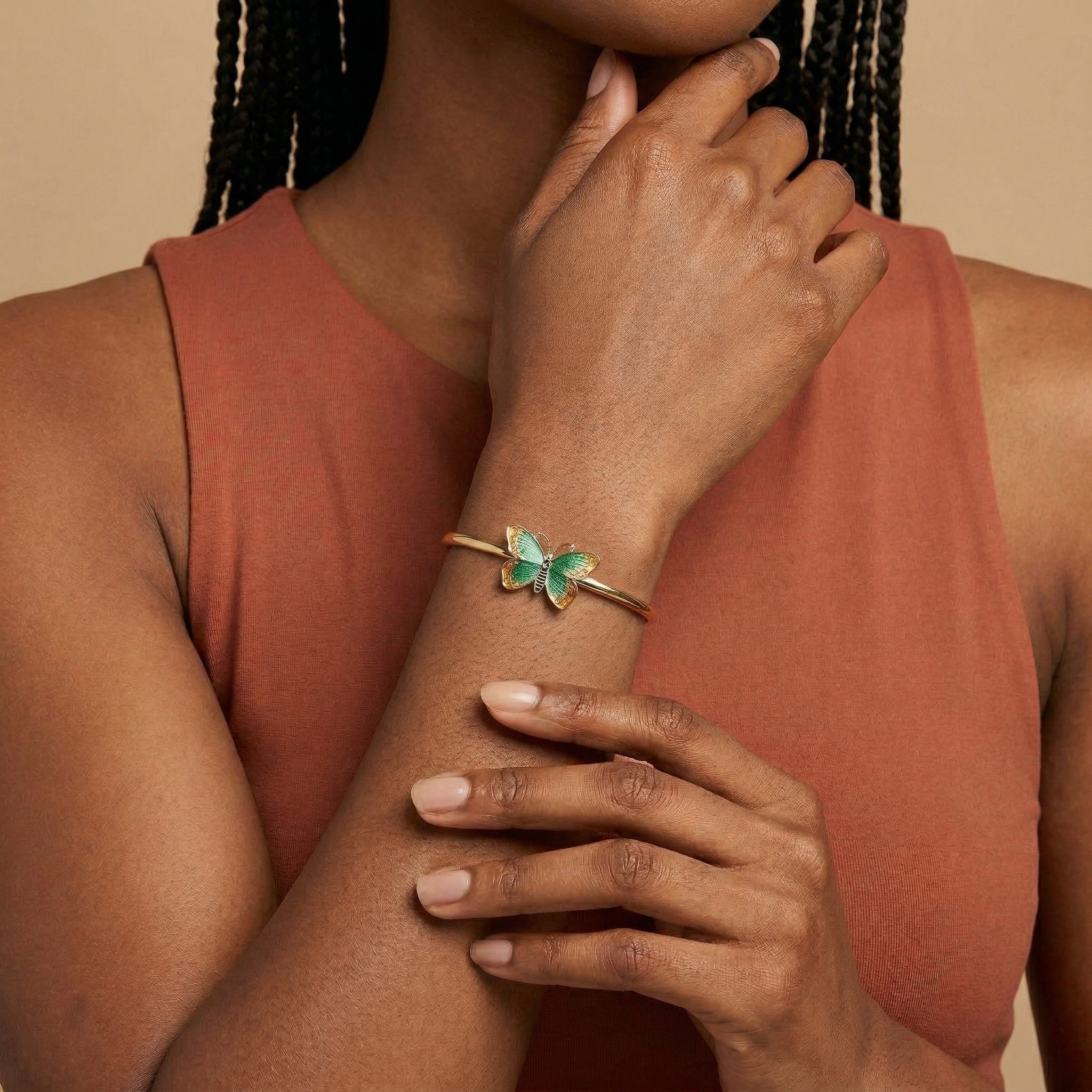 Woman wearing a green butterfly bracelet on a gold tone spring hinge on her wrist