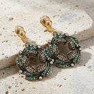 Peacock Plumage Art Nouveau Style Blue Iridescent AB Glass Wreath Clip On Earrings on a textured stone surface