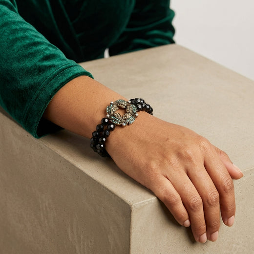 Woman wearing our Peacock Plumage Blue Iridescent AB Black Glass Bead Wreath Bracelet on her wrist