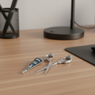 Silver cat scissors and matching pewter cover on a wooden desk with a lamp and pen holder in the background.