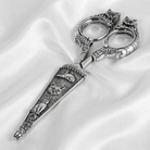 Decorative silver cat scissors on a white satin background