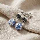 Blue Willow drop bead clip on earrings resting on beige fabric