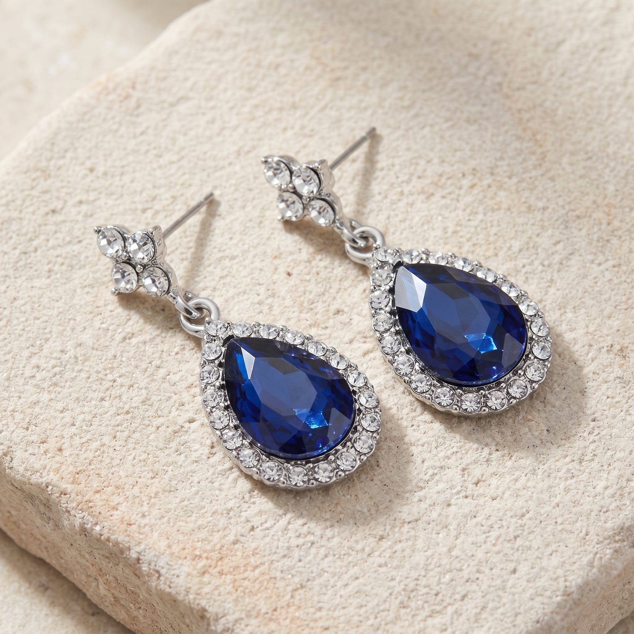 Atlantic Blue Stone Teardrop Crystal Post Drop Earrings on a beige stone surface