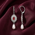 Siam Red Starburst Crystal Pearl Dangle Earrings on a burgundy fabric background