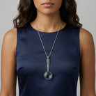 Woman wearing a magnifying glass pendant necklace with blue crystal accents 