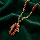 Carnelian Glass Heritage Treasure Pendant Necklace resting on dark green fabric