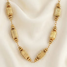 Gold tone multi-beaded necklace resting on a cream satin fabric