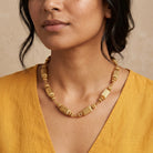 Women in a yellow top wearing a gold tone multi-beaded necklace.