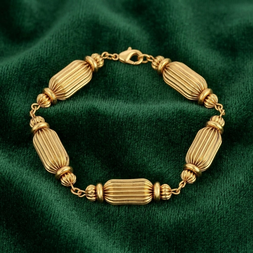 Gold colored beaded bracelet resting on dark green fabric