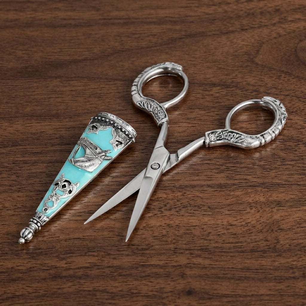 Silver tone vintage-style scissors opened on a wooden table with the cover next to it that has turquoise stone and a horse head design