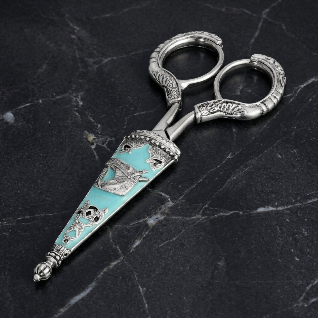 Vintage-style silver tone scissors with a turquoise cover and horse designs resting on dark marble surface