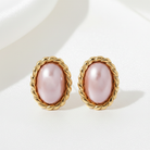 Pair of earrings with pink stones and gold braided settings on a white background