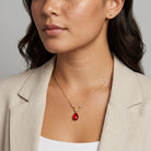 Woman wearing a red teardrop pendant necklace with clear crystal accents