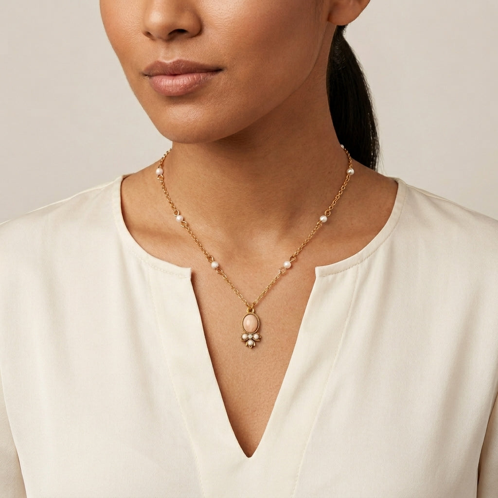 Woman in a white top wearing an oval pink faux pearl pendant necklace with white faux pearls on the chain 
