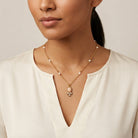Woman in a white top wearing an oval pink faux pearl pendant necklace with white faux pearls on the chain 