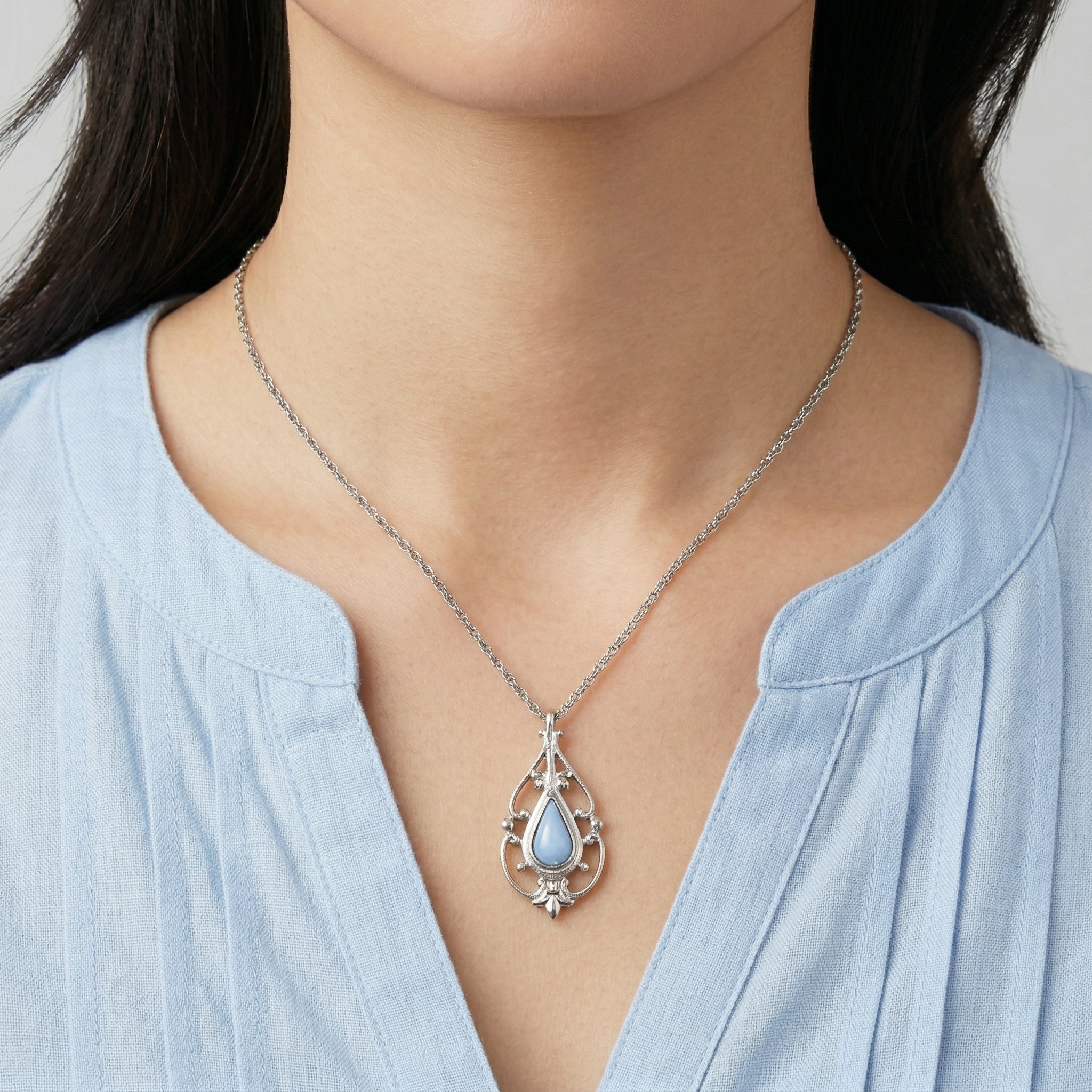 Blue stone pendant necklace worn by a woman with a v-neck blouse