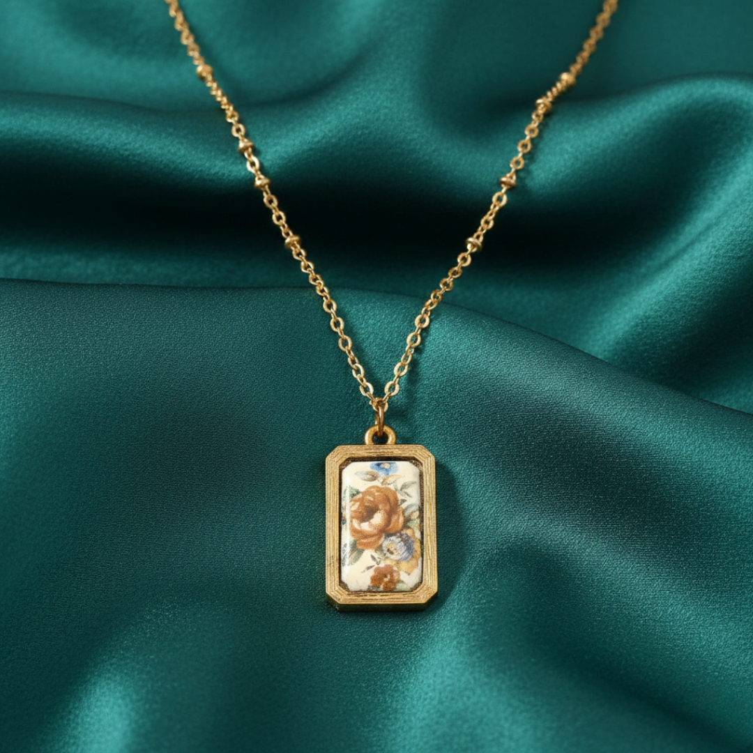 Gold necklace with a pendant on a green fabric background