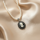 Pearl necklace with a cameo pendant on a beige fabric background