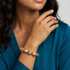 Gold color beaded bracelet worn by a woman with a teal dress