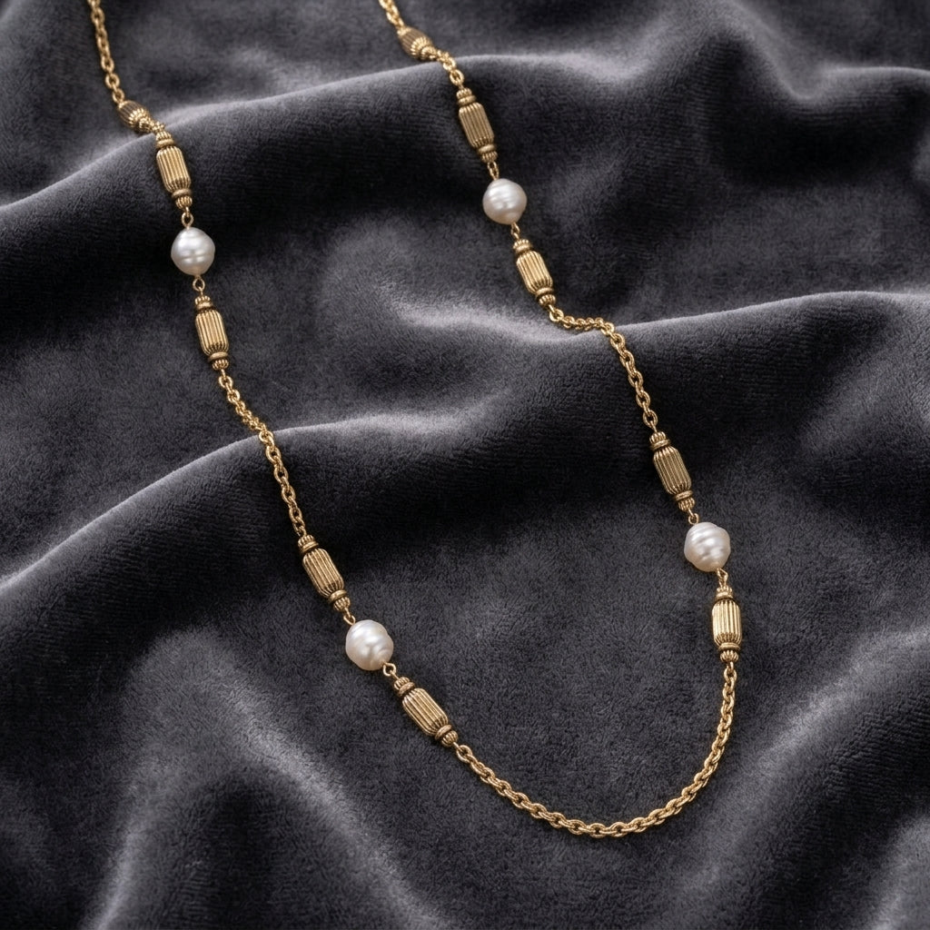 White and gold tone beaded necklace resting on dark gray fabric surface