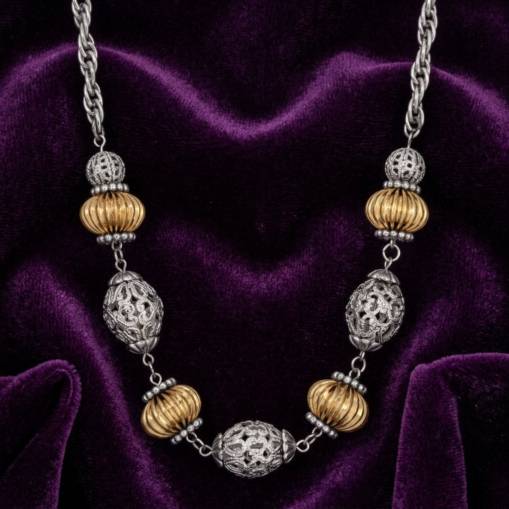 Melon-shaped beaded necklace with silver and gold tone accents resting on purple fabric 