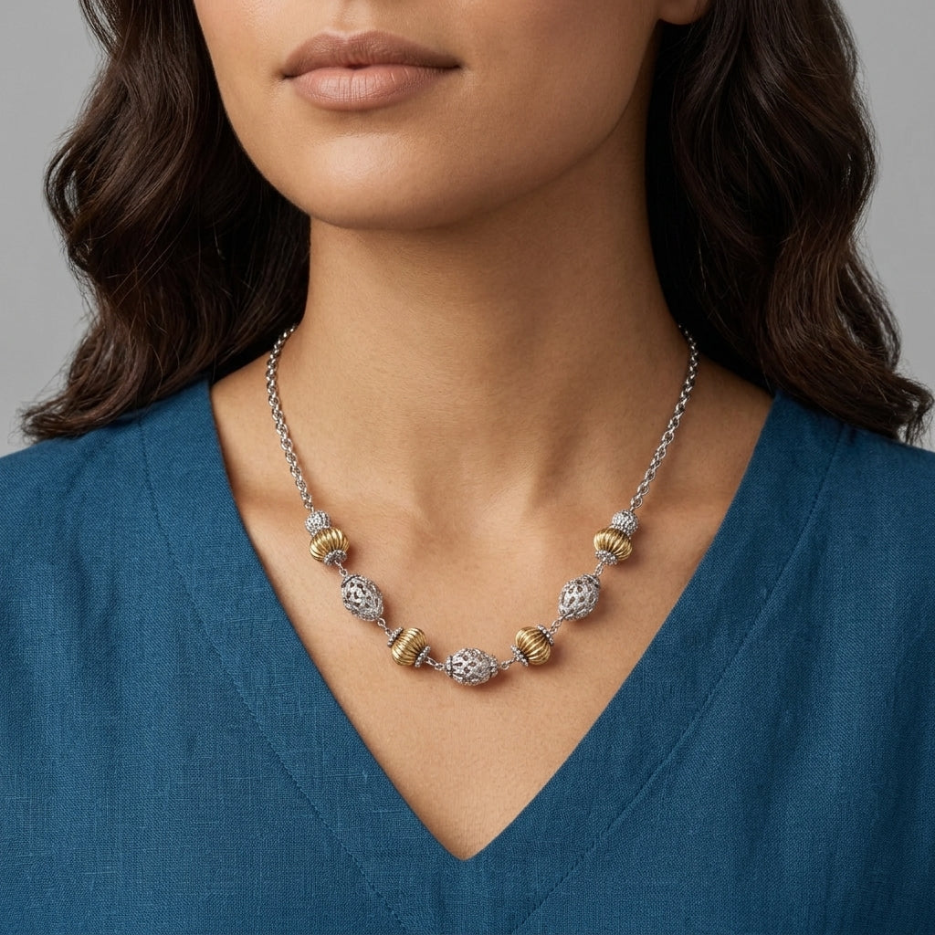 Woman with a blue top wearing a melon-shaped bead necklace with silver and gold tone accents