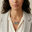 Six antiqued silver tone cats on a necklace with white faux pearl accents worn by a woman in a blazer