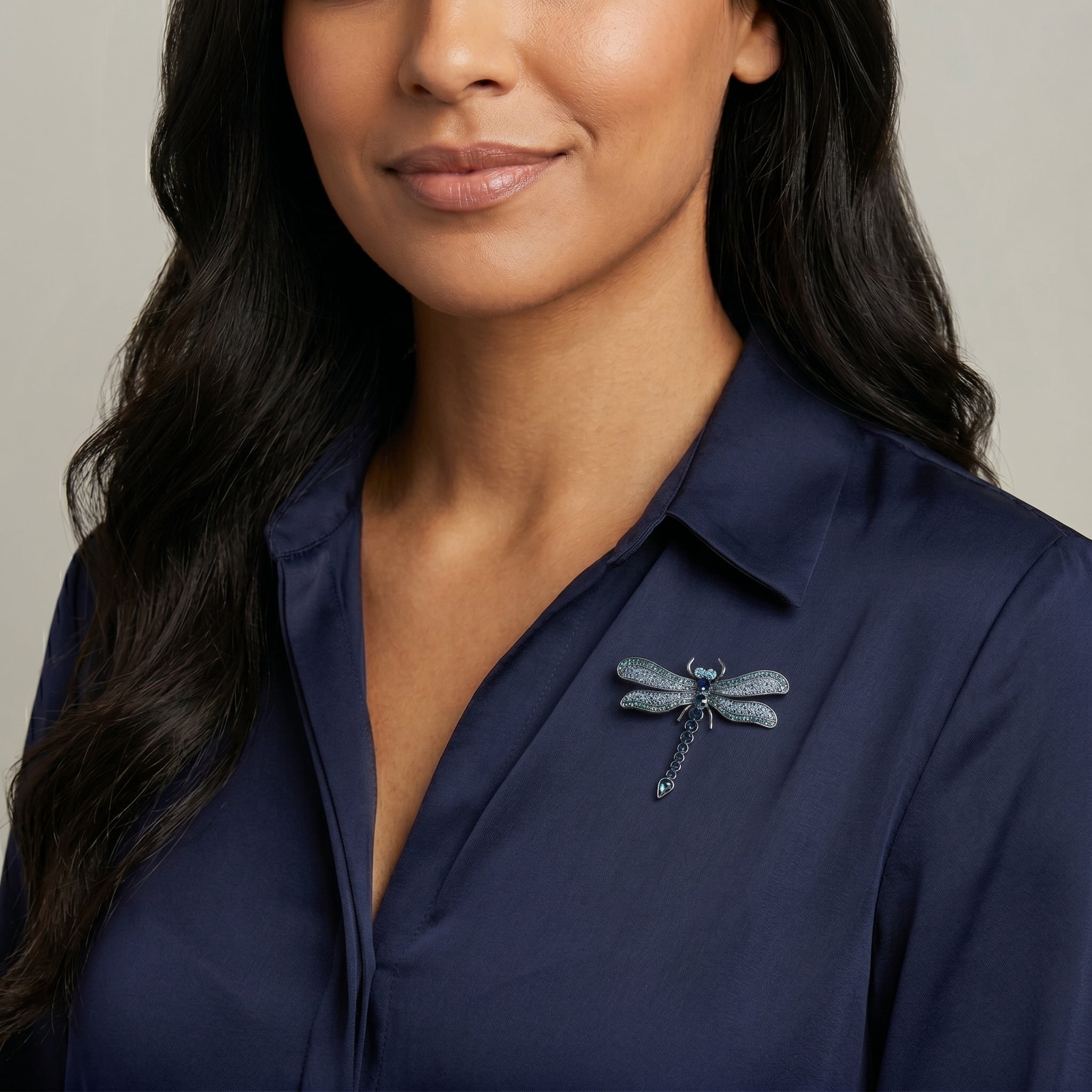 Blue crystal dragonfly brooch being worn by a model with dark hair and a blue collared shirt