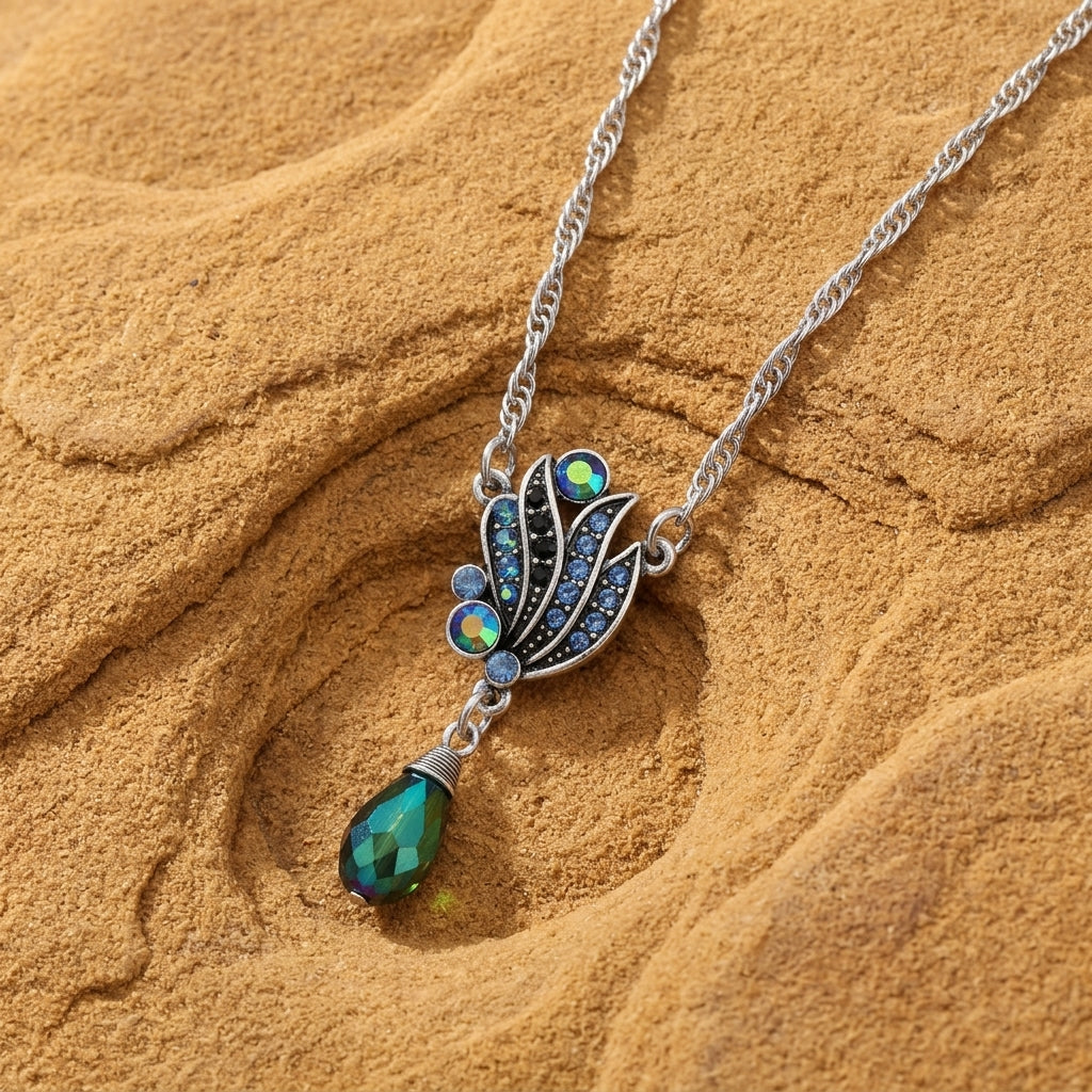 Montana blue and AB crystal drop pendant necklace resting on brown sandstone surface