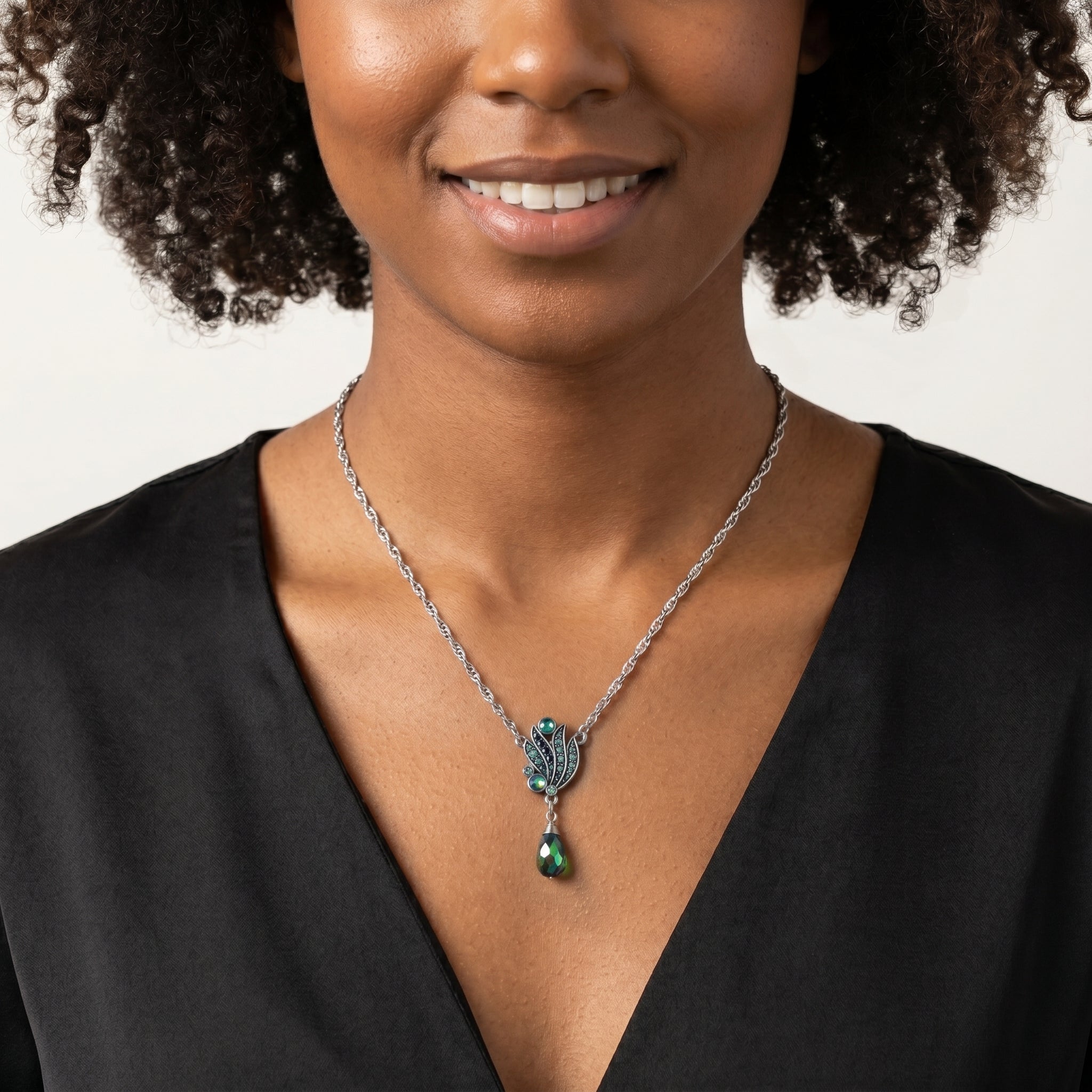 Woman with a black top wears a shimmering AB crystal and Montana blue crystal pendant drop necklace 