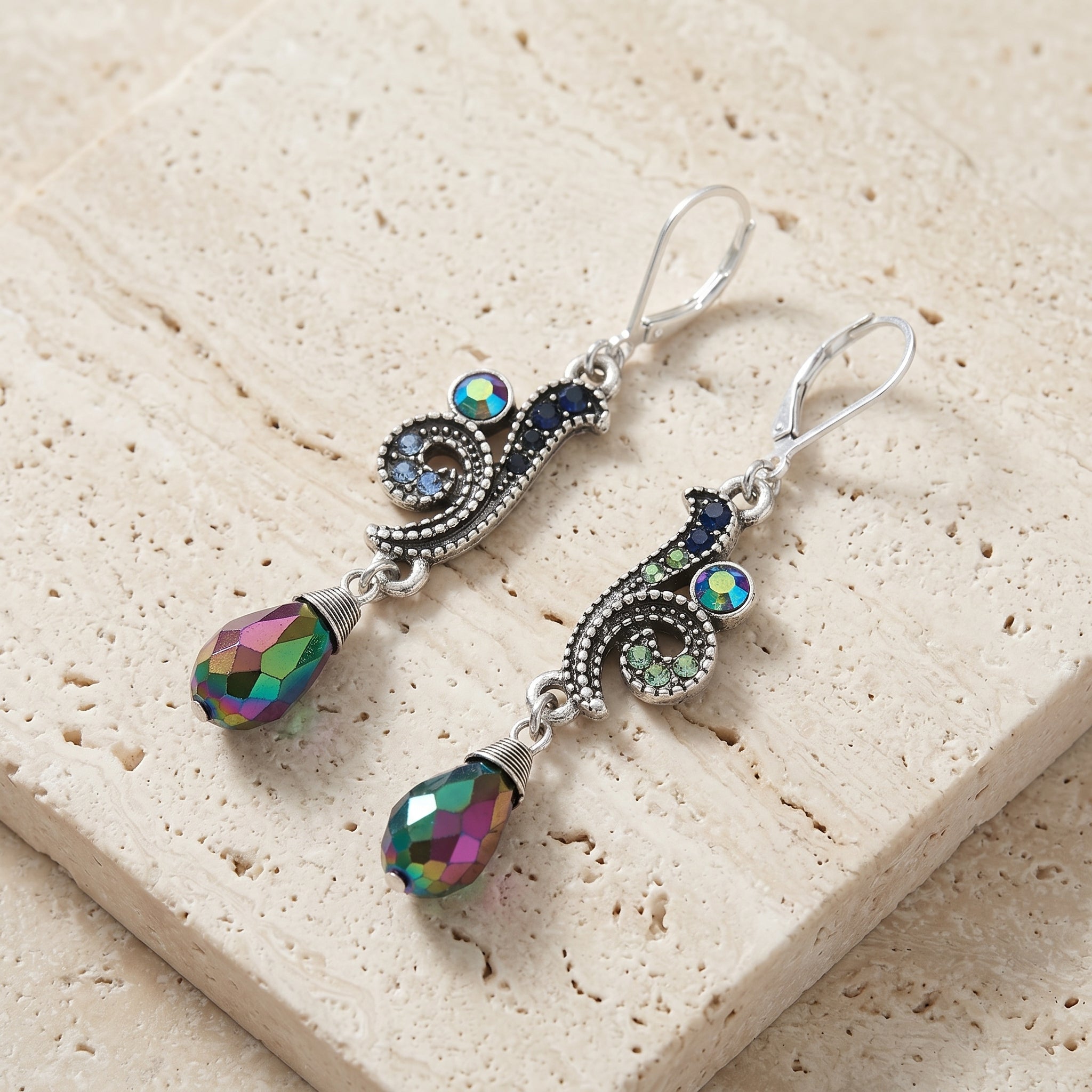 Giovane Iridescent AB Crystal & Blue Stone Dangle Earrings on light stone surface