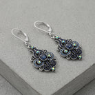 Giovane Iridescent AB Crystal & Blue Stone Spade Drop Earrings on a gray stone surface