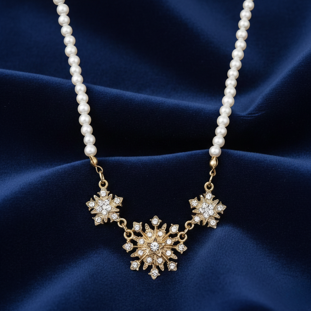 Faux pearl necklace with a gold and crystal starburst pendant on a blue fabric background