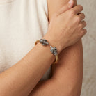 Close-up of a wrist wearing a pewter Rams head bangle bracelet with a neutral background
