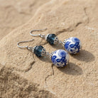 Blue Willow Dark Blue And Beaded Dangle Earrings resting on beige stone surface