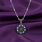 Silver necklace with a decorative pendant full of crystals on a purple fabric background